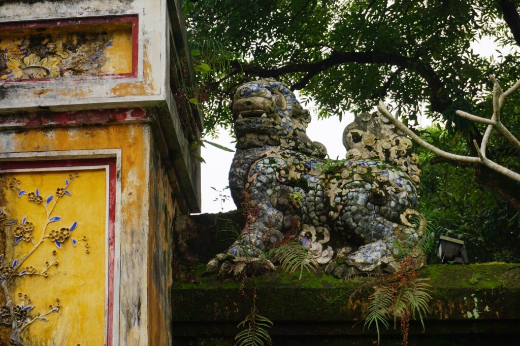 Mit Moos bewachsener Drache auf einer Mauer in der verbotenen Stadt in Hue.