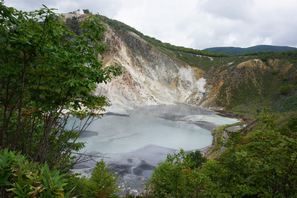 Blick auf einen dampfenden See im Höllental auf Hokkaido