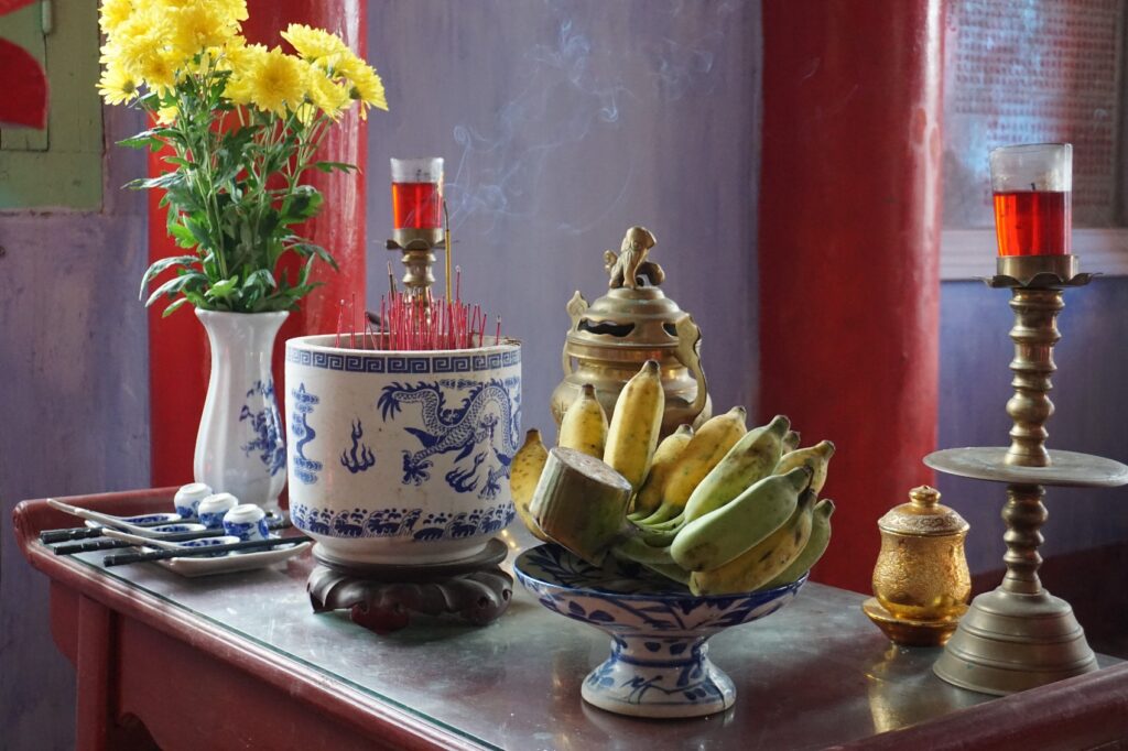 Ein Altar in einem chinesischen Tempel mit Blumen, Räucherstäbchen und Bananen.